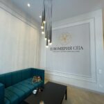 Пример 'дизайнерского ремонта коммерческих помещений': зона ожидания в 'Плюмерия СПА' с логотипом на стене, отделанной молдингами.