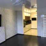 Результат 'отделки квартиры под ключ': объединенная кухня-гостиная с современной мебелью, 3D-панелями и глянцевым натяжным потолком.