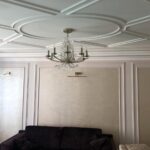Пример 'дизайнерского ремонта квартир': гостиная со сложным кессонным потолком с геометрическим узором и стенами, отделанными в технике 'буазери'