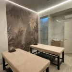 Пример 'элитного ремонта коммерческих помещений': SPA-кабинет с интегрированной душевой зоной, отделанной керамогранитом под мрамор, и акцентной стеной с тропическим панно.