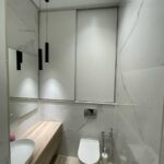 Современный 'проект ремонта санузла' в SPA-салоне: подвесная тумба под дерево и отделка стен керамогранитом под мрамор.