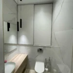 Современный 'проект ремонта санузла' в SPA-салоне: подвесная тумба под дерево и отделка стен керамогранитом под мрамор.