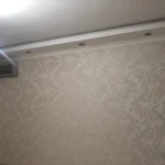 Финальный этап 'отделки квартиры под ключ': комната с классическими обоями с узором 'дамаск' и потолочной лепниной.