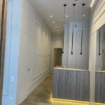 Результат 'отделки коммерческого помещения под ключ': холл SPA-салона со стойкой ресепшн, стенами 'буазери' и многоуровневым освещением.