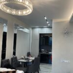 Завершенный 'дизайн кухни-гостиной': открытое пространство с зонированием, хрустальной люстрой над обеденной зоной и современной трековой системой.